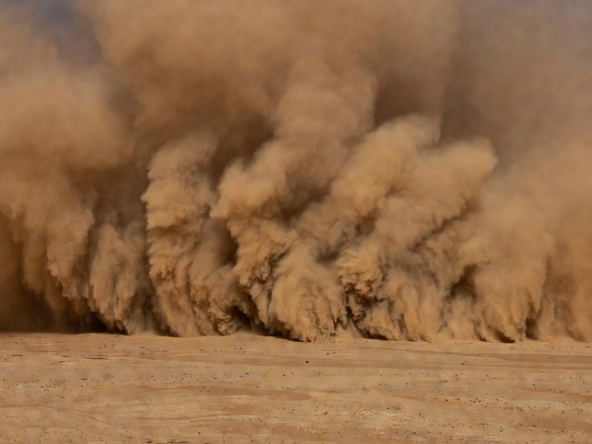 Towering wall of brown dust haboob advancing over arid desert floor